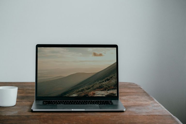 Laptop open on a desk next to a cup of coffee