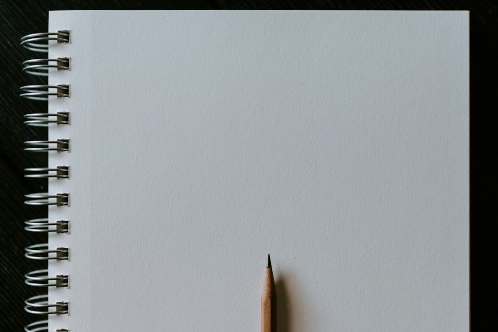 Wooden pencil resting on a blank spiral notebook