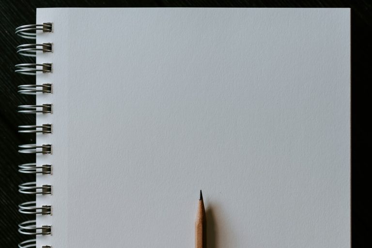 Wooden pencil resting on a blank spiral notebook